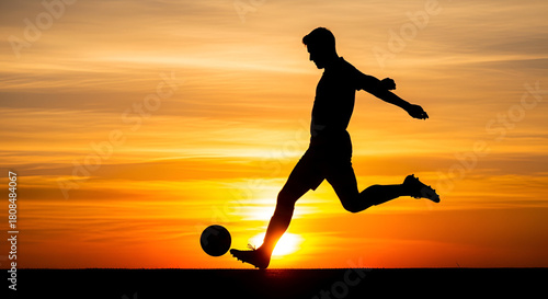 Silhouette of a soccer player kicking the ball at sunset with a golden sky