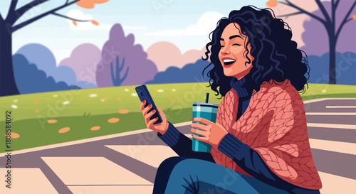 A happy woman with curly hair sits in a park, laughing at her phone and holding a drink, showcasing modern digital connection and relaxation