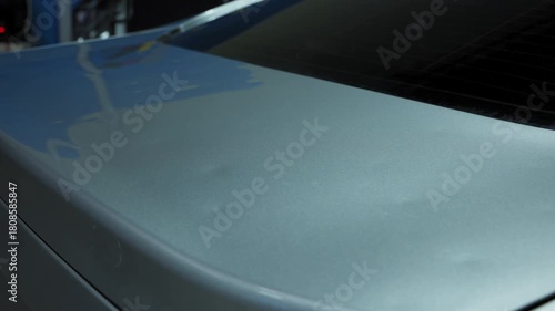 Close up footage damaged of car body under pointless dent repair, mechanic at the auto repair shop with tools . PDR