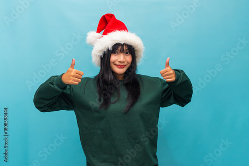 Woman in Santa hat gives double thumbs up cheerfully Ideal for festive promotions and positive holiday campaigns