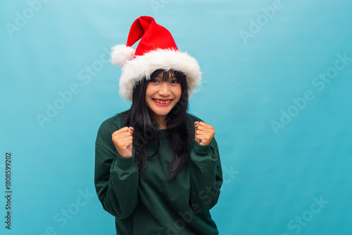Happy Asian woman smiles brightly with hands raised Ideal for joyful Christmas advertising and lifestyle content