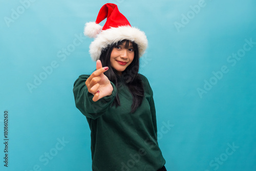 Playful woman in Santa hat gestures small heart with hand Ideal for Christmas love and cheerful festive content