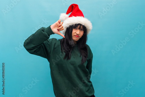 Playful woman in Santa hat points to head with thinking pose Ideal for Christmas ideas and creative festive visuals