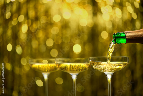 pouring champagne wine from bottle in a coupe glasses, selective focus. champagne poured in a champagne glases.