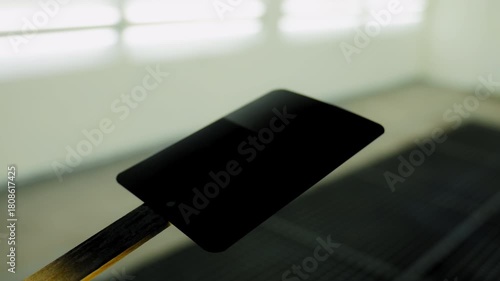 Professional auto body technician applies black paint onto a small test panel using a spray gun inside a clean, well lit automotive paint booth. 