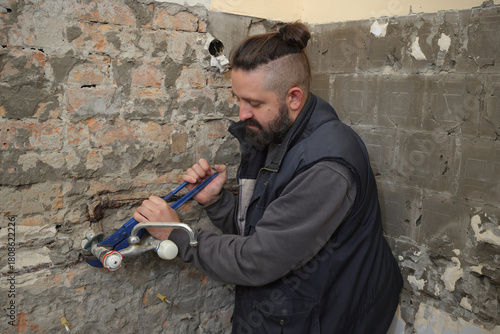 Home renovation, young plumber fixing or replacing old faucet in a bathroom, using adjustable wrench tool
