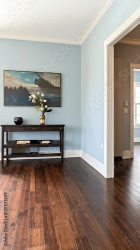 A room with blue walls, hardwood floors, and a table with art and flowers