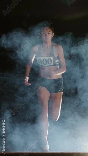 Wallpaper Mural female athlete running from darkness through fog vertical slow motion fullHD symbol of strength motivation determination confidence victory mindset focus inspiration empowerment Torontodigital.ca