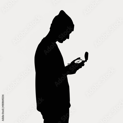 Silhouette of a person looking at a compass for navigation and direction.