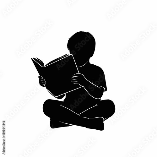 Young child absorbed in reading a captivating book while sitting cross legged.