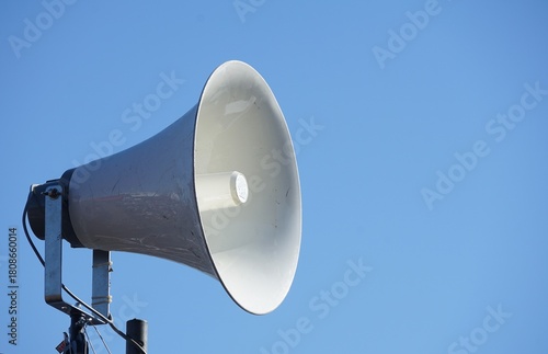 A Single White Horn Speaker Against Clear Blue Sky