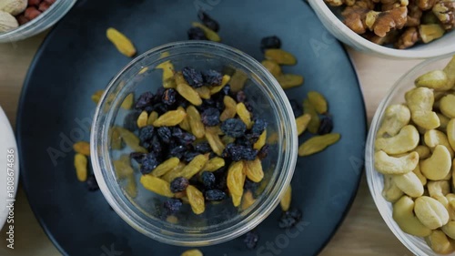 Top view of a bowl with mixed dried fruits surrounded by nuts