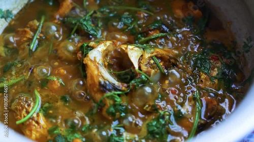 Close-up of a bubbling fish curry with herbs and spices