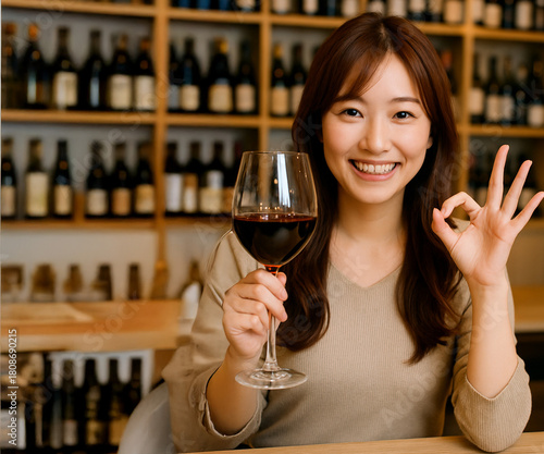 赤ワインを持ち笑顔でOKサインをする若い女性