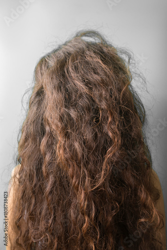 Beautiful long curly hair of a girl in the studio on a gray background