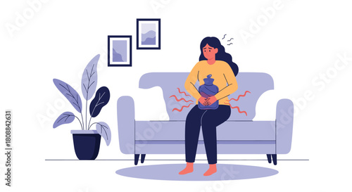 Woman with menstrual cramps holding a hot water bottle on her stomach while sitting on a couch at home.