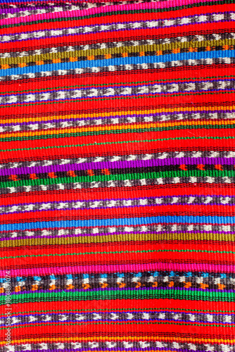 Colorful striped Guatemalan fabric with a red background