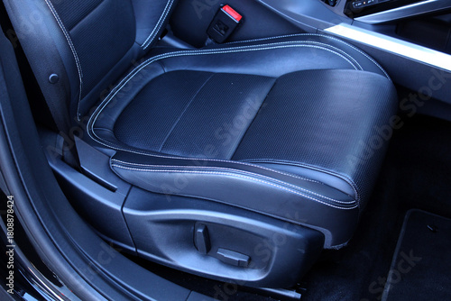 Lux car drivers seat in black perforated leather. Close up view of modern car leather seat at the luxury black interior. Close up car interior details. New car inside. Vehicle cleaning theme.