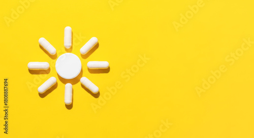 White vitamin D pills arranged in sun shape on vibrant yellow background, symbolizing health, wellness, and the importance of sunlight for vitality