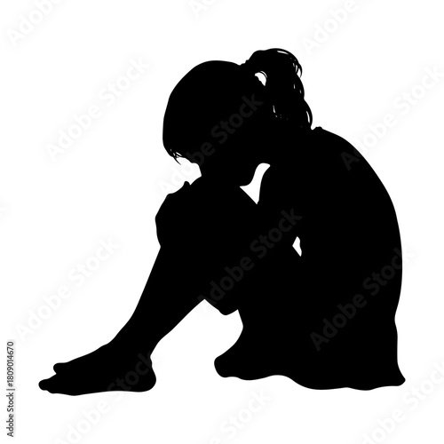 Black silhouette of a sad girl sitting on the floor hugging her knees without background.