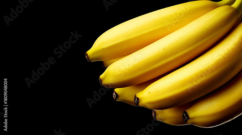 A close up shot of a bunch of ripe yellow bananas against a stark black background in a studio setting christmas and happy new year background 