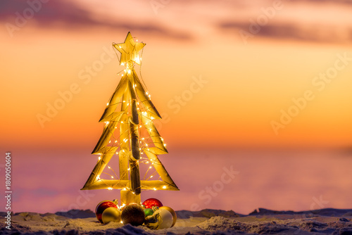 Christmas tree with fairy lights on a coastal beach