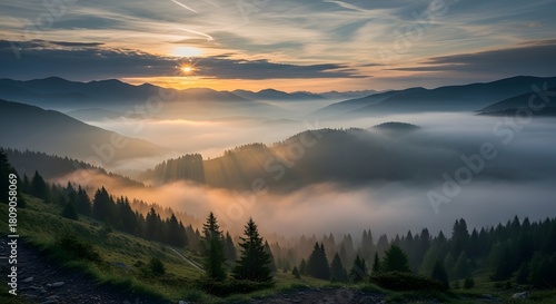Sunrise over mountain range with fog rolling through valleys and evergreen tree silhouettes in foreground