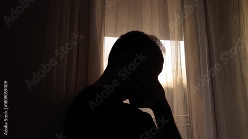 Silhouette of depressed, sad and lonely man in the apartment.