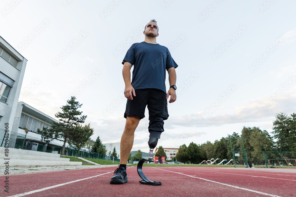 Obraz premium Man with a disability running on the athletic track wearing a prosthetic leg, blade with a heel plate designed for sports activities.