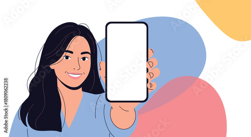 Happy smiling woman with dark hair holds up a smartphone with a blank white screen for mockup on an abstract background.