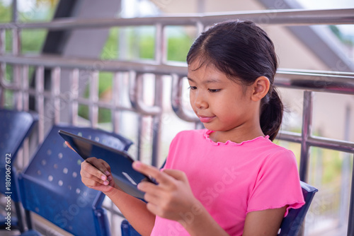 Young Girl Using Tablet While Sitting in Public Waiting Area