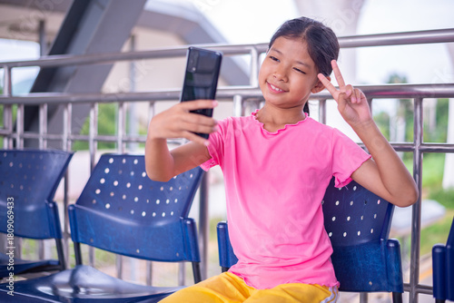 Happy Asian Girl Taking a Selfie with Smartphone While Sitting Outdoors