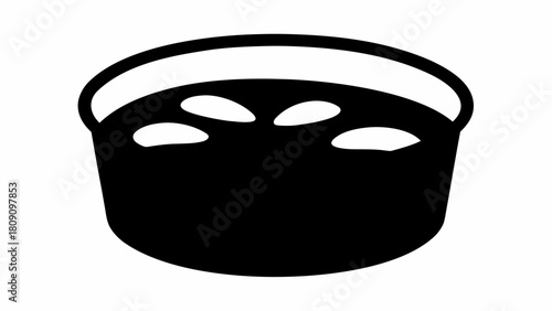 A black bowl filled with a dark liquid and several white oval shaped objects floating on the surface