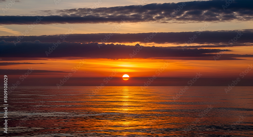 Fototapeta premium Sunset over calm sea with golden sun near horizon, tranquil beach scene