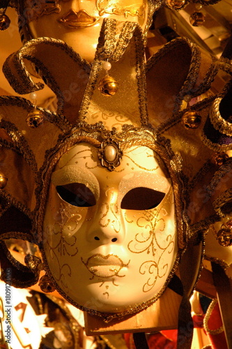 A close-up of an ornate golden Venetian mask, adorned with glittering details and bells. A luxurious glimpse into Venice’s iconic carnival artistry and timeless craftsmanship.
