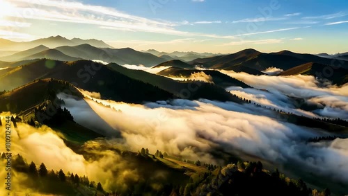 Serene aerial view of misty mountain range at sunrise with golden light over rolling hills