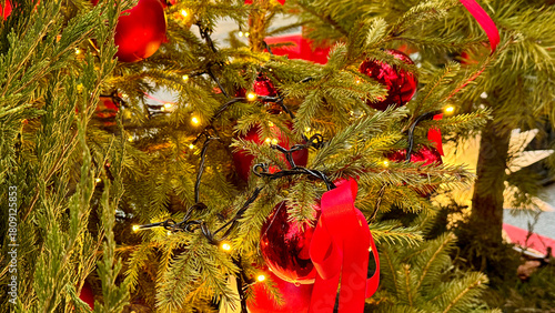 Photography Closeup of Christmas tree branches with red ornaments, ribbon and warm lights, large glowing star
