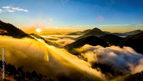 Sunrise over rugged mountain range with sea of clouds and golden glow over sunlit peaks