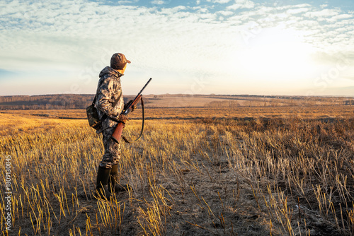  hunter with shotgun at beautiful sunset. autumn hunting period. male hobby.