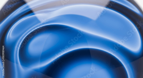 Abstract image of a glass sphere with swirling blue and white light reflections creating a fluid, dynamic pattern.