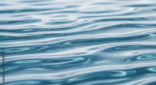 Gentle waves ripple across a calm body of water, creating a textured surface with varying shades of blue.