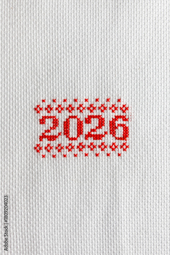 2026 is embroidered in red thread on white fabric. 