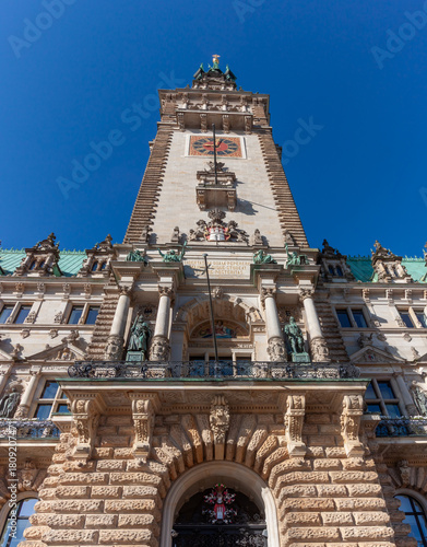 The impressive clock tower and main entrance of Hamburg City Hall in Germany, captured on a clear, sunny day against a bright blue sky