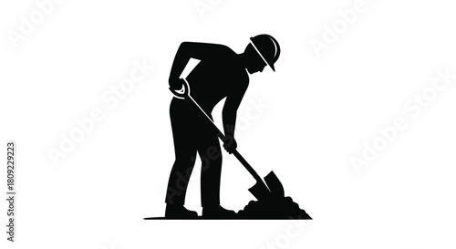 Silhouette of a construction worker digging with a shovel in the ground