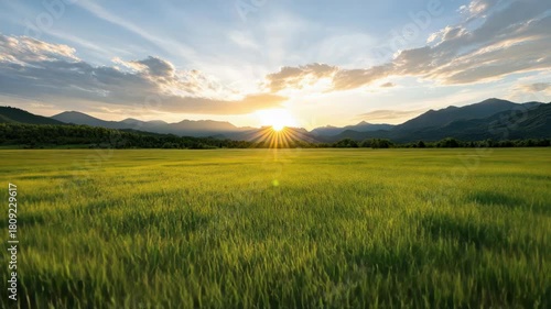 Sunset field mountain sky sunbeam green grass peaceful golden light over distant silhouette sunrise