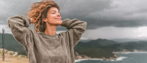 Woman enjoying nature with a relaxed expression and windy hair outdoors.