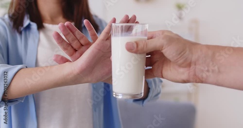 Woman shows refusal to milk, lactose intolerance. Avoiding dairy prevents stomach pain, indicating sensitive digestion and possible allergy. Clear concept: dietary intolerance and discomfort.