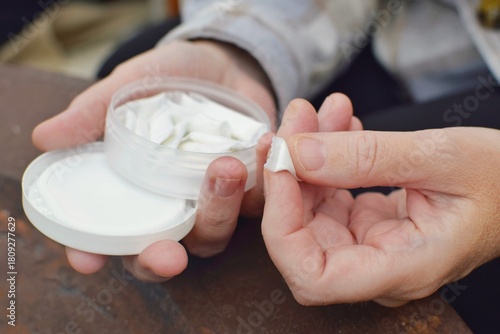 A box of snus pads replaces smokeless cigarettes. Swedish nicotine pouch. A woman holds one bag of snus in her hand.