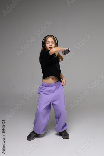 Young caucasian girl dancing with headphones and controller in studio setting