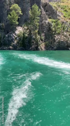 The seething wake of a tourist boat's engine on emerald water